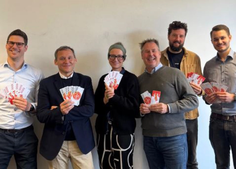 Six people smile at the camera and hold banknotes in their hands.