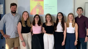 A group of people in front of a screen showing a presentation. 