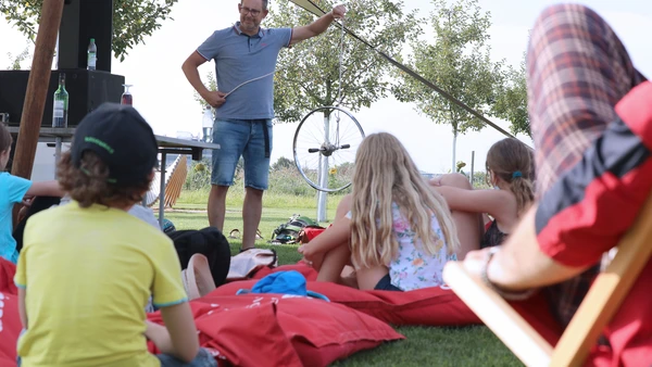 Kinder auf Wiese hören einer Person zu