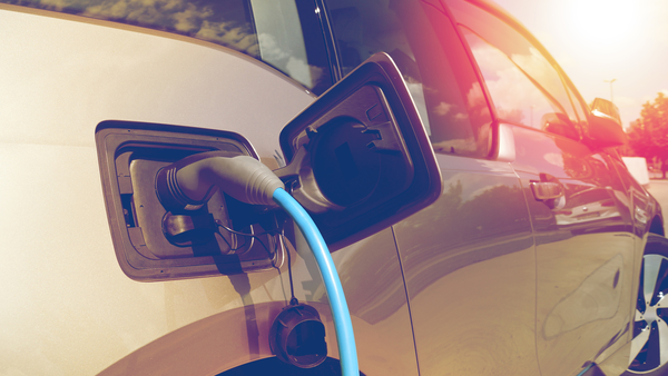 An electric car is being charged. The charging cable is in the tank.