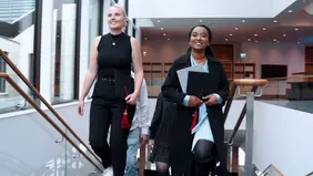 Two young women on a staircase in the building, shot head-on