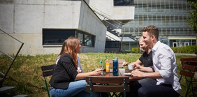 Menschen sitzen auf Bank auf Campus Wiese